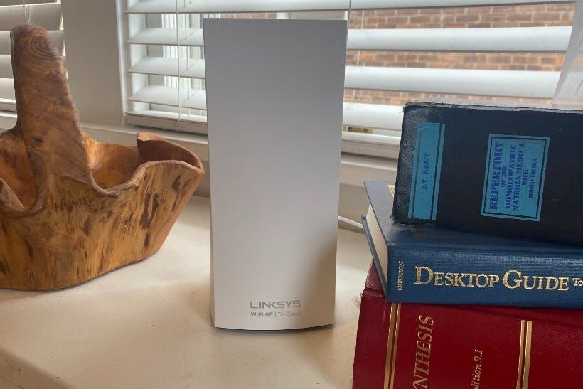 The Linksys Atlas router between some books and a wooden basket